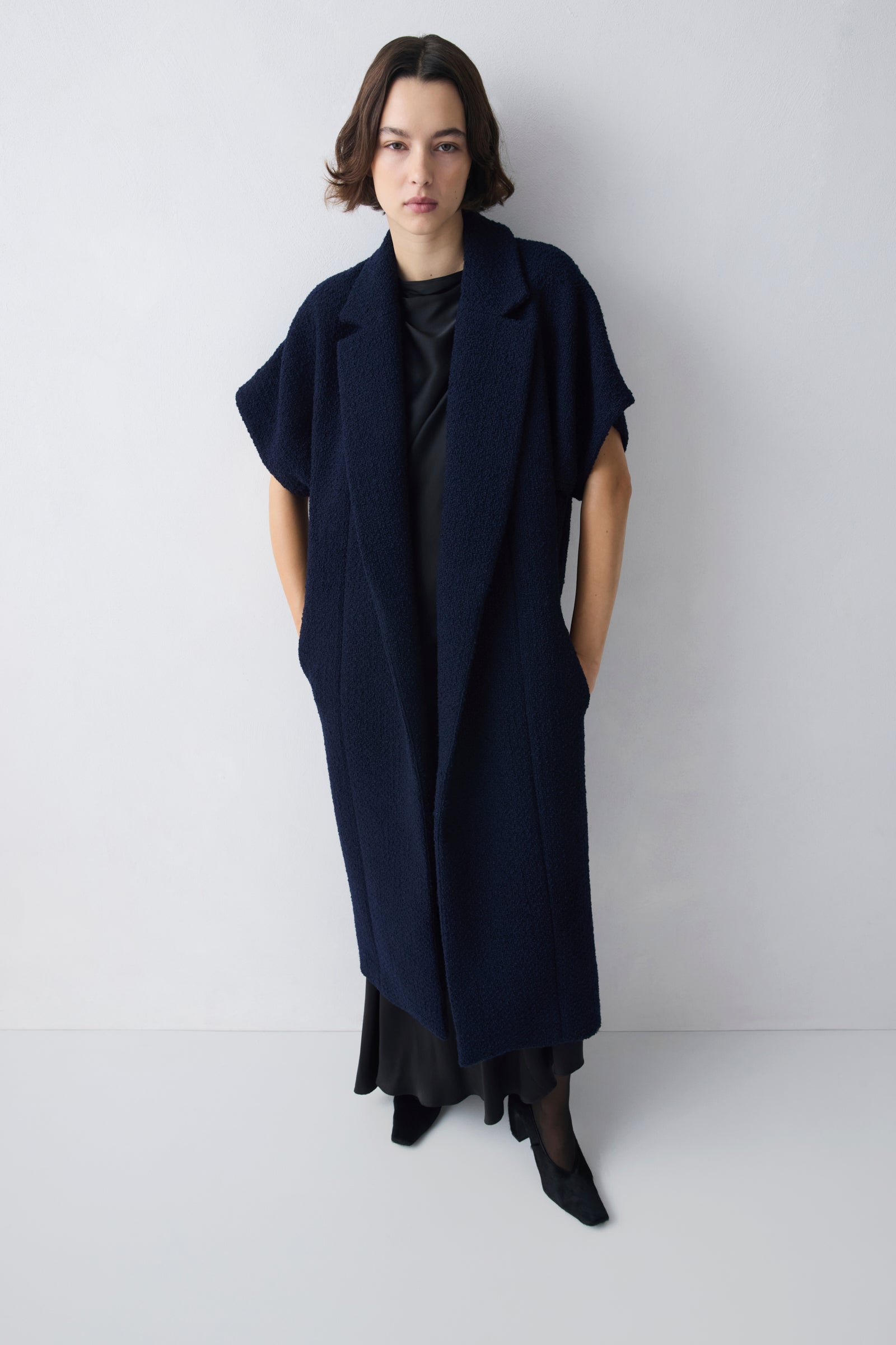 Woman wearing a long navy blue dress against a white background