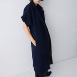 Person wearing a long navy coat against a white background