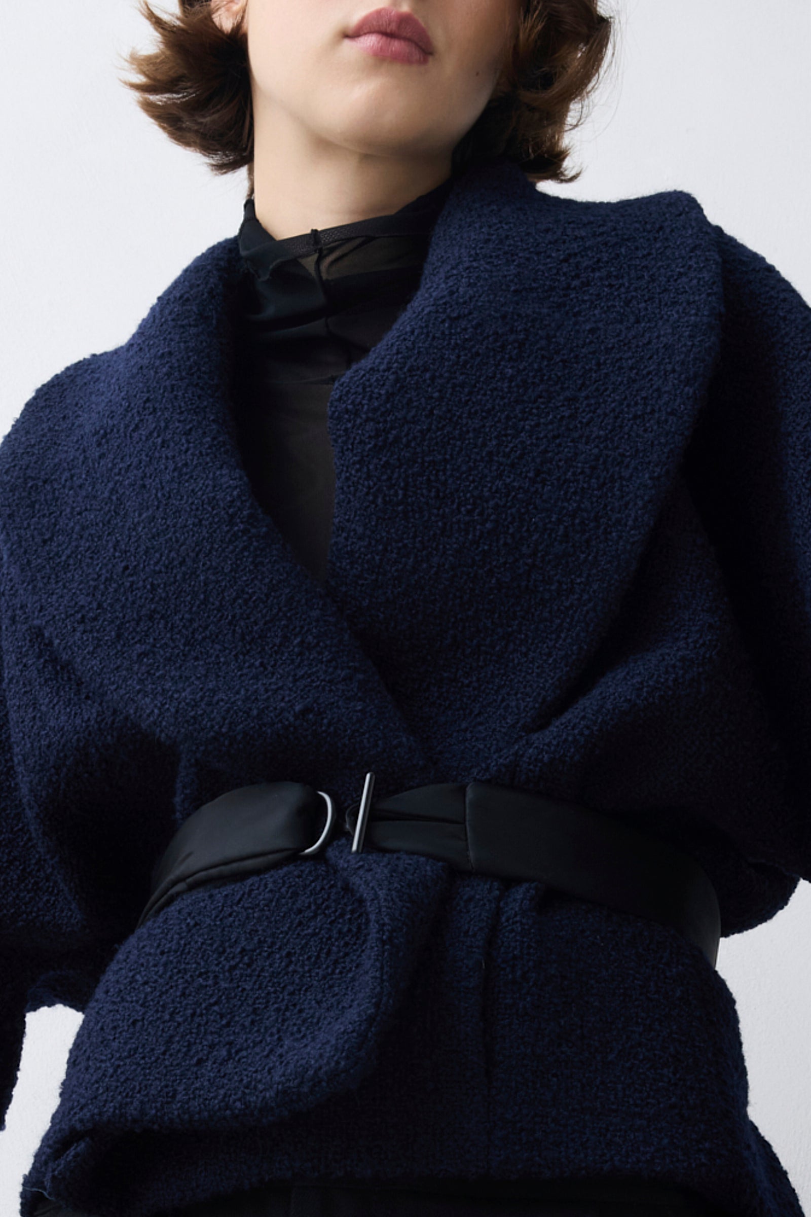 Navy blue jacket with a belt on a plain background