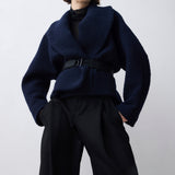 Person wearing a dark blue jacket and black pants on a white background