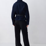Person wearing a dark blue jacket and black pants on a white background