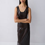 A model wearing a dark brown textured faux-leather sleeveless top and matching skirt set, paired with black pointed-toe boots, against a plain light gray studio background.