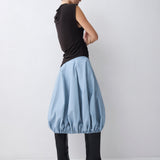 Woman wearing a brown sleeveless top and light blue skirt on a white background