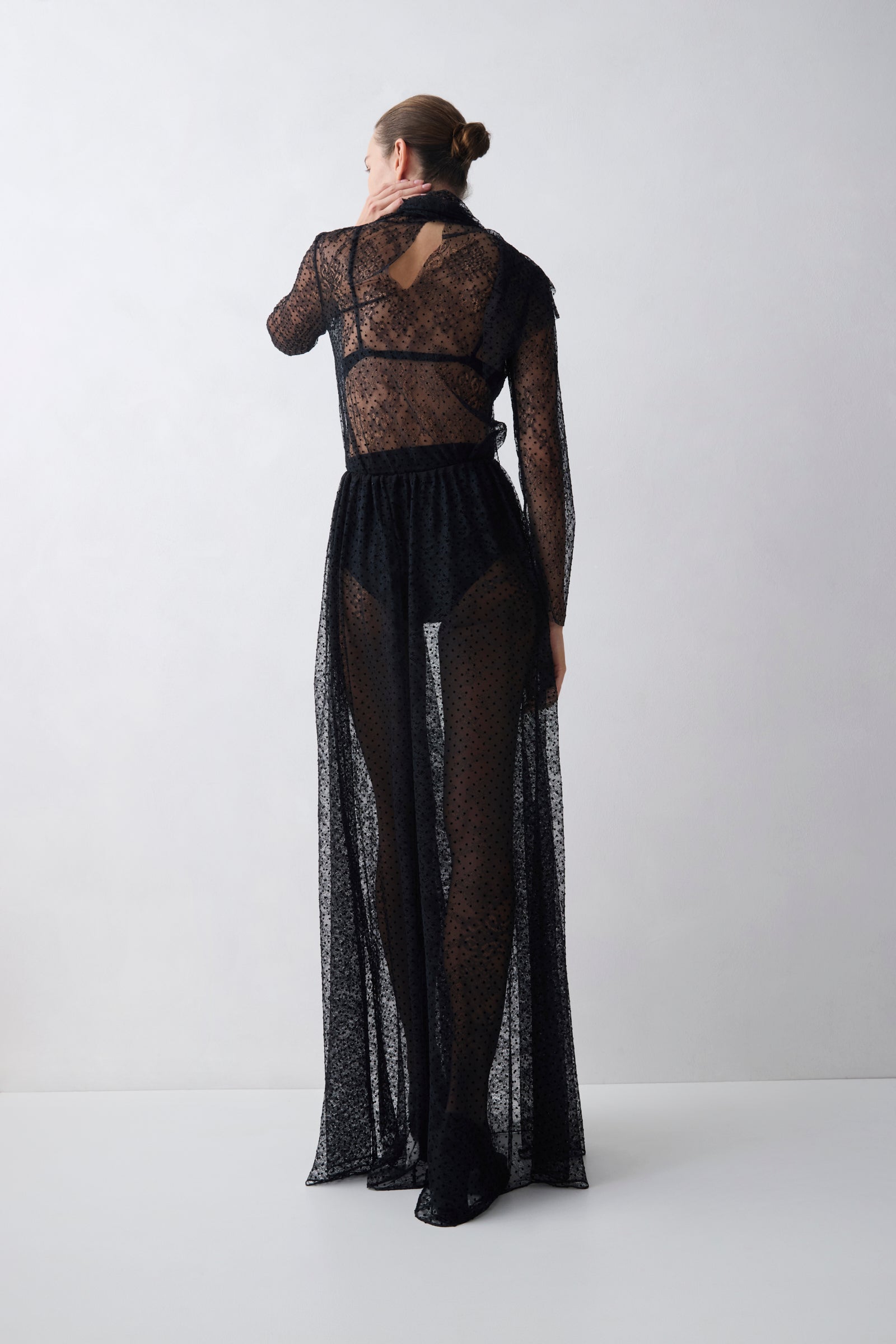 Person wearing a black lace outfit on a white background