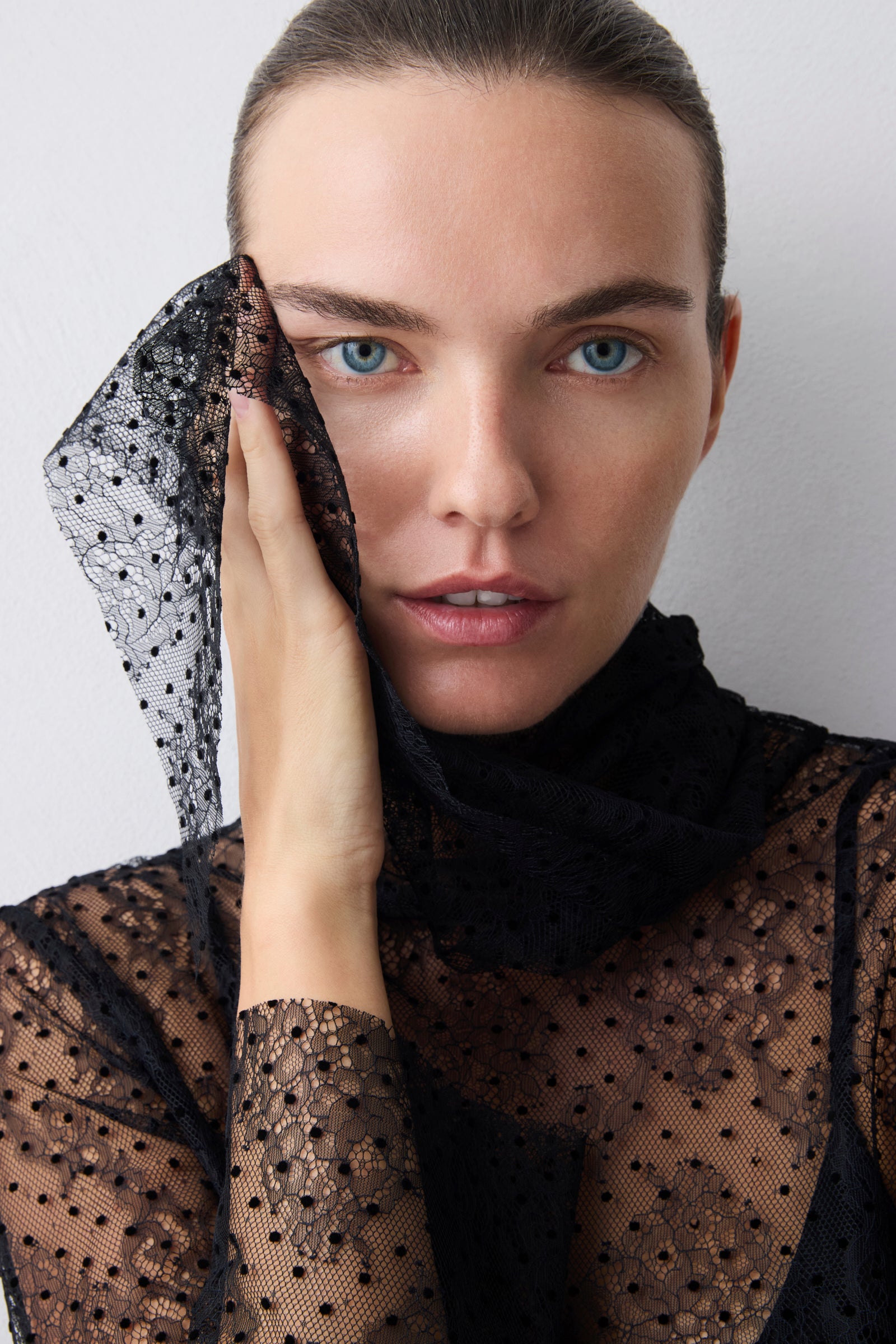 Woman wearing a black lace garment against a plain background