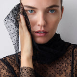 Woman wearing a black lace garment against a plain background