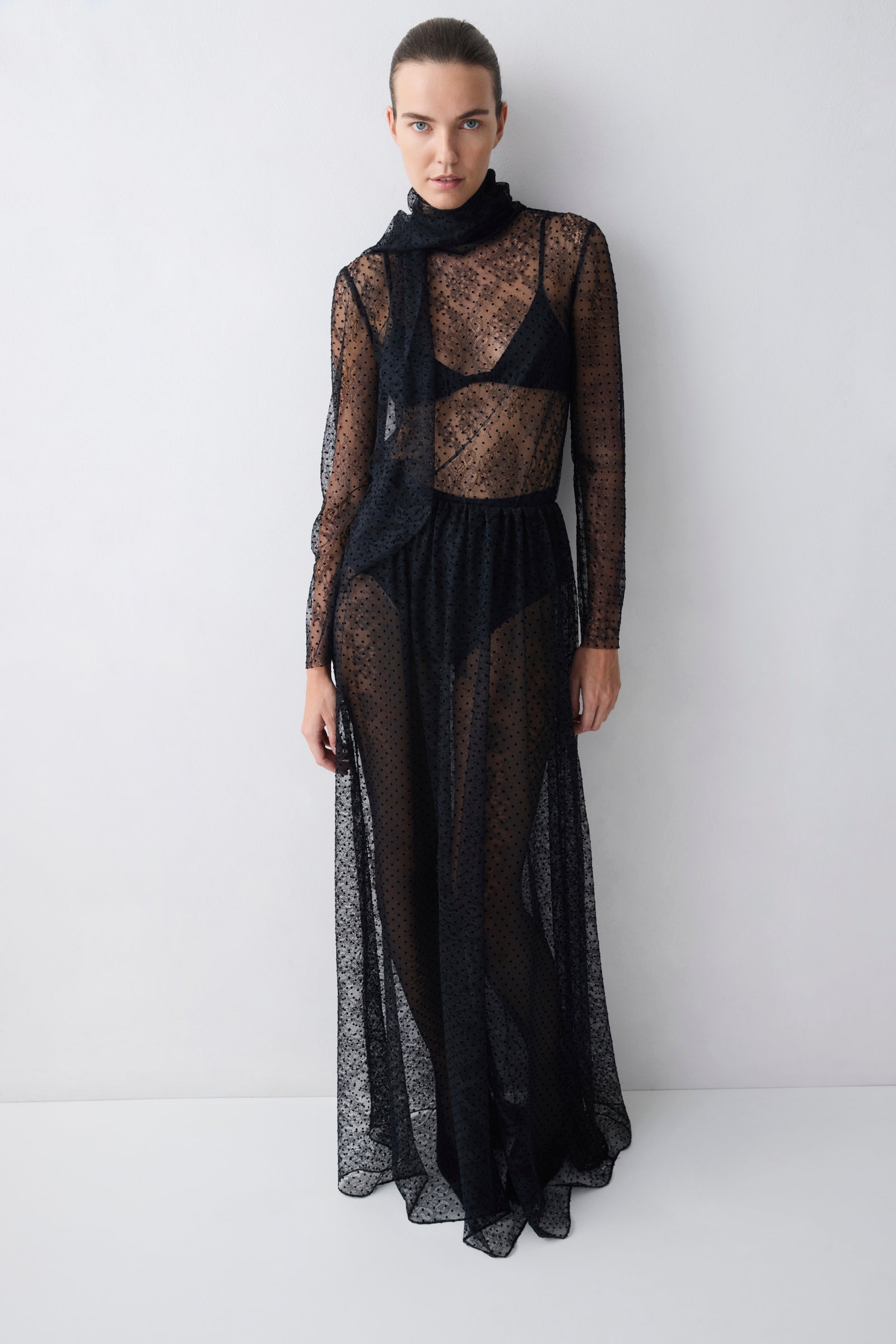 Woman wearing a black lace dress against a white background
