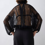 Person wearing a sheer black top with long sleeves on a white background