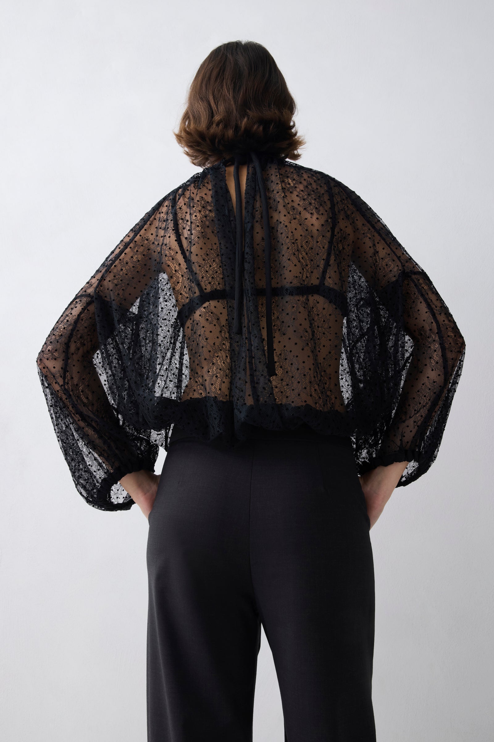 Person wearing a sheer black top with long sleeves on a white background