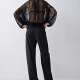 Person wearing a sheer black top and black pants on a white background