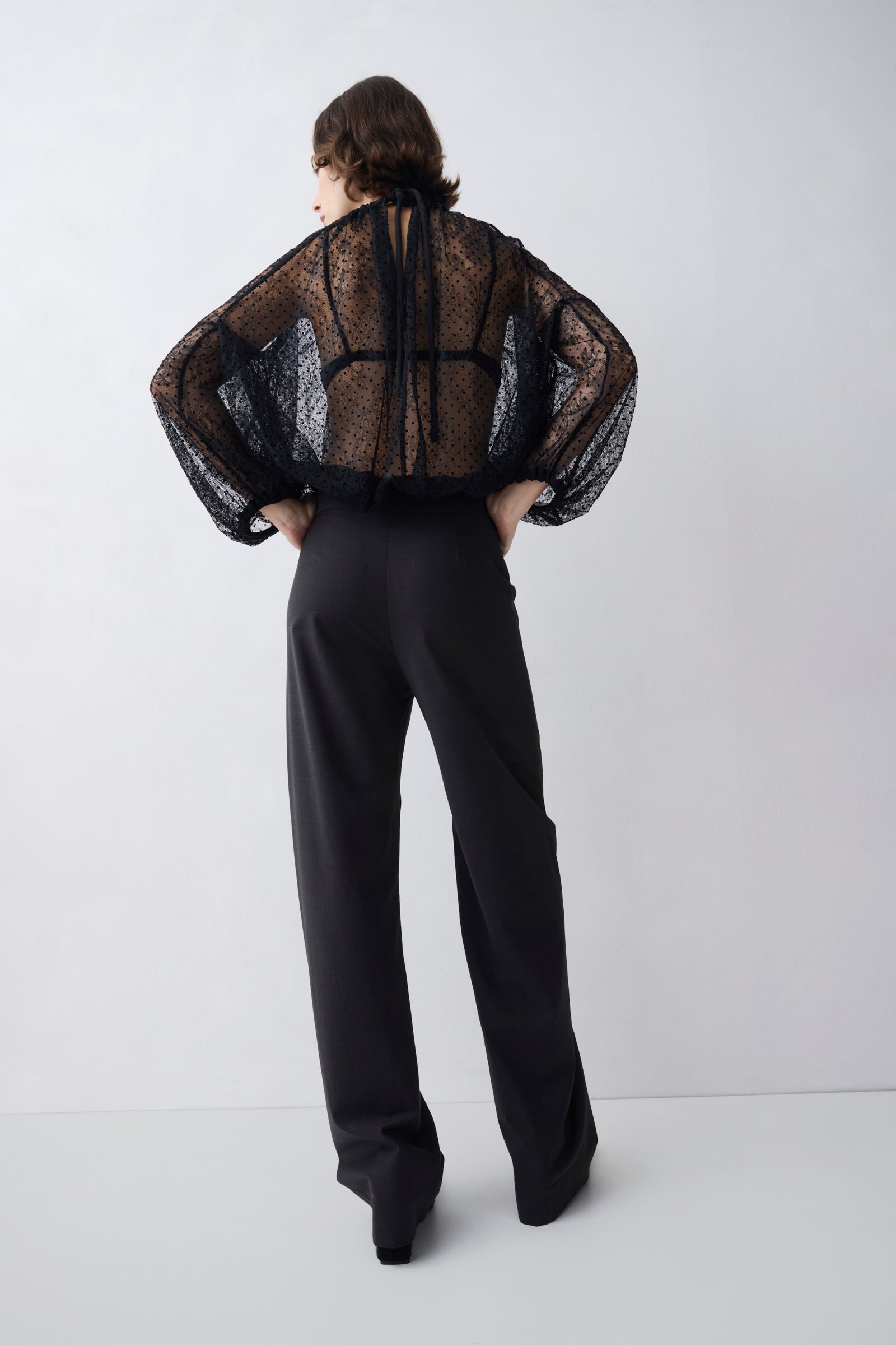 Person wearing a sheer black top and black pants on a white background