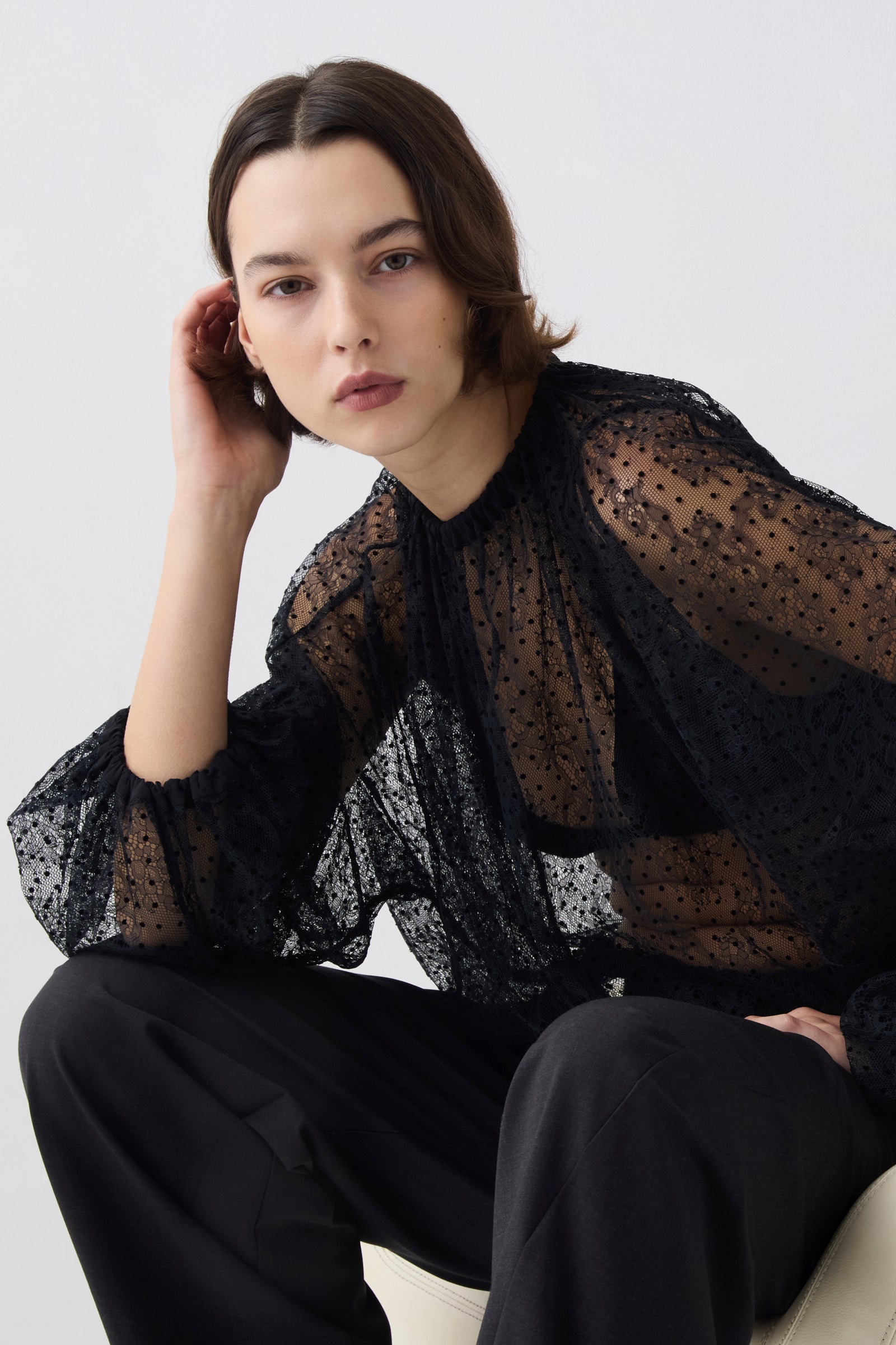 Woman wearing a black sheer blouse with a white background