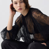 Woman wearing a black sheer blouse with a white background