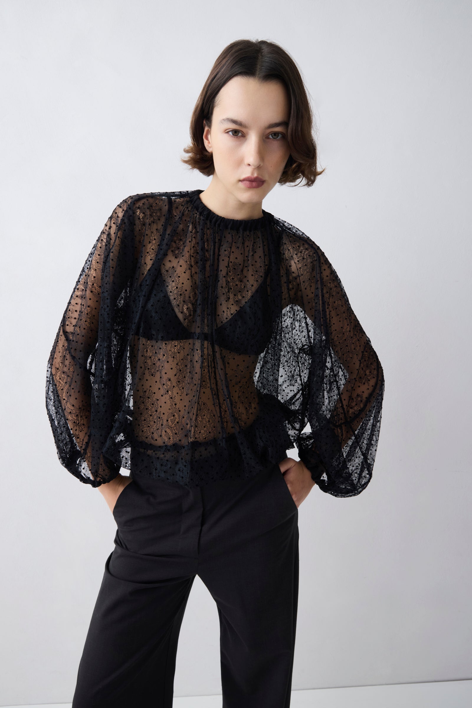 Person wearing a black sheer blouse with puffed sleeves against a white background