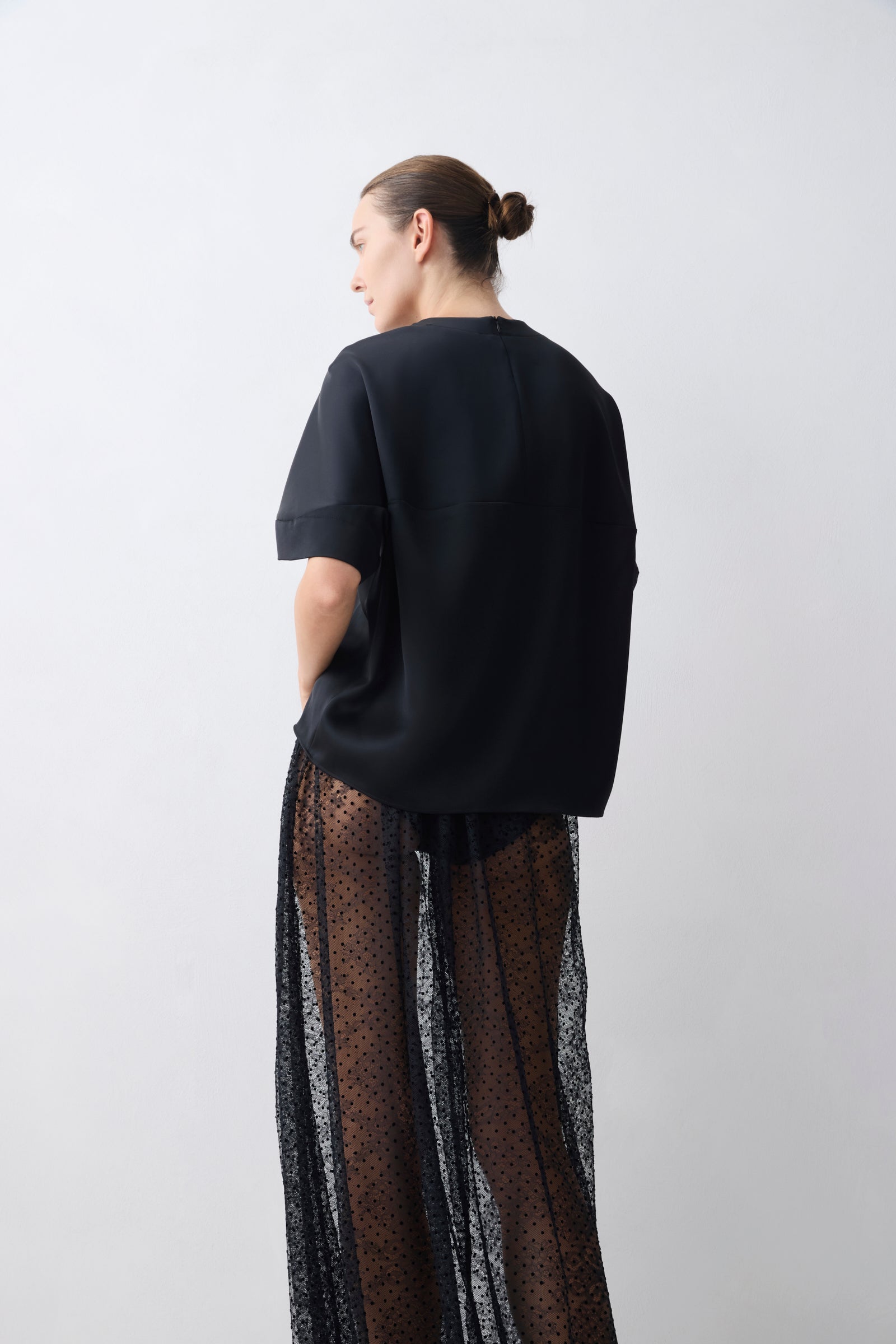 Person wearing a black outfit with sheer pants on a white background