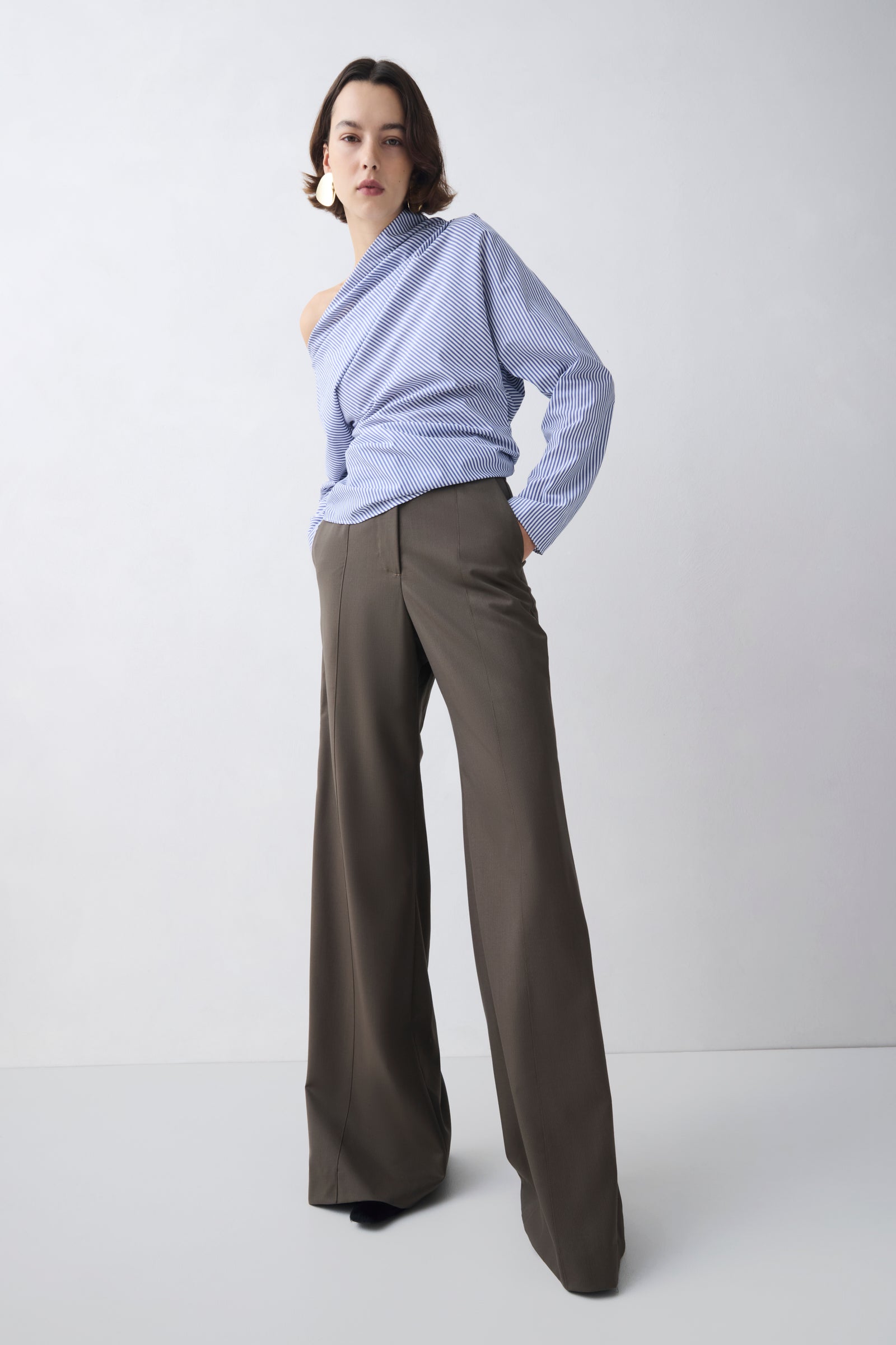 Person wearing a light blue off-shoulder top and gray wide-leg pants on a white background