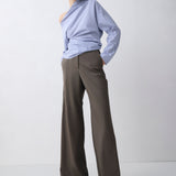 Person wearing a light blue off-shoulder top and gray wide-leg pants on a white background