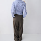Person wearing a light blue striped shirt and dark green pants on a white background