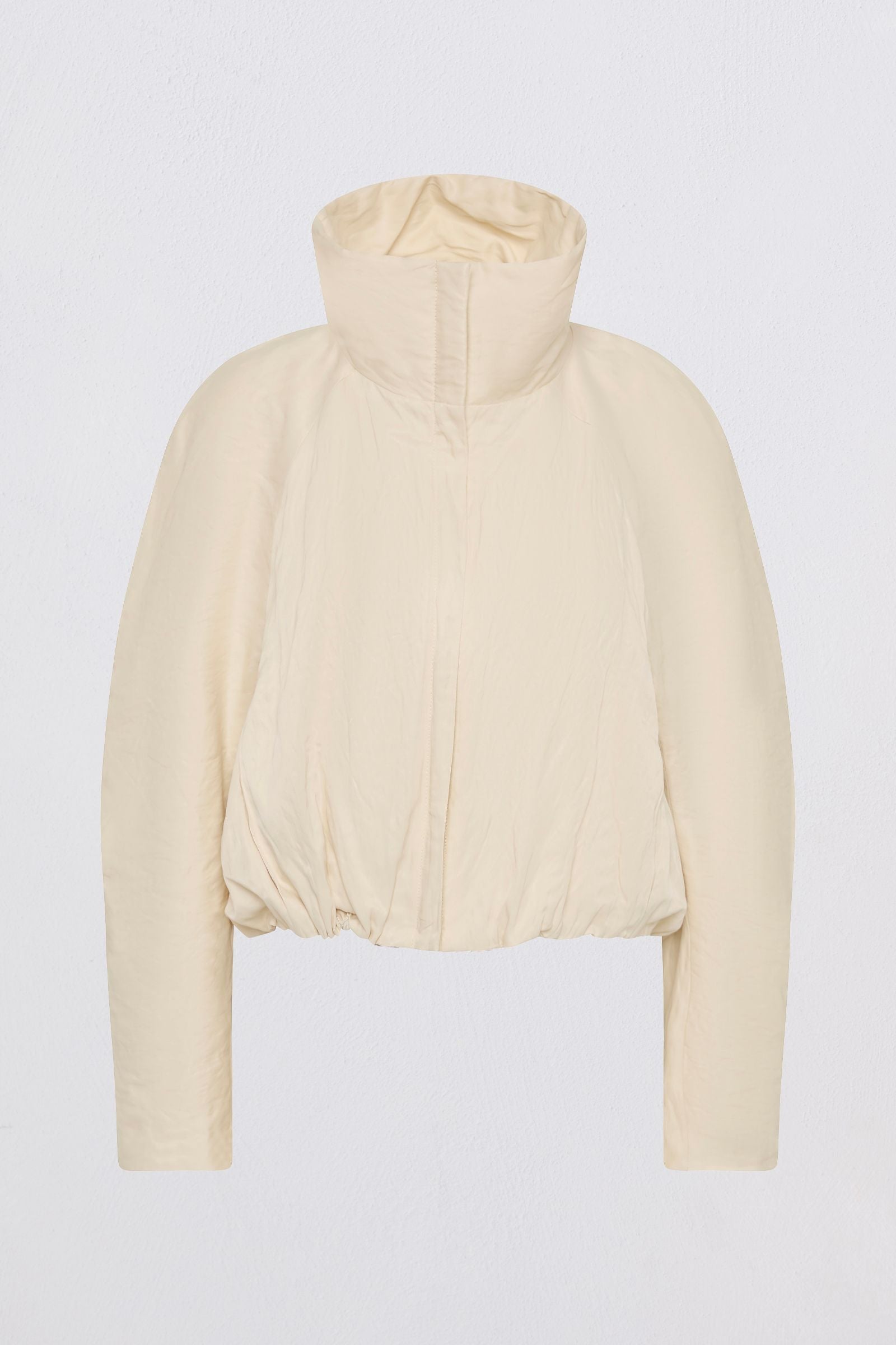 A cropped, long-sleeve jacket in a light cream or off-white color, featuring a high stand-up collar and a gathered, quilted design, shown against a plain light gray background.