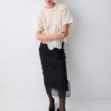 Woman wearing a beige lace top and black skirt against a white background