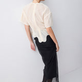 Woman wearing a white textured top and black skirt on a white background