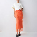 Person wearing a white top and orange skirt on a white background