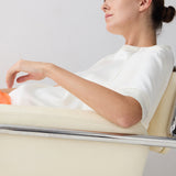 Woman sitting in a modern chair with a plain background