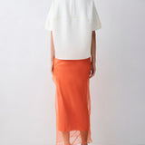 Person wearing a white top and orange skirt on a white background