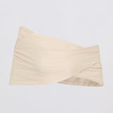 A light beige strapless bandeau top with a twisted crossover front detail, shown against a plain light gray background.