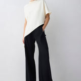 Woman wearing a white top and black pants on a plain background