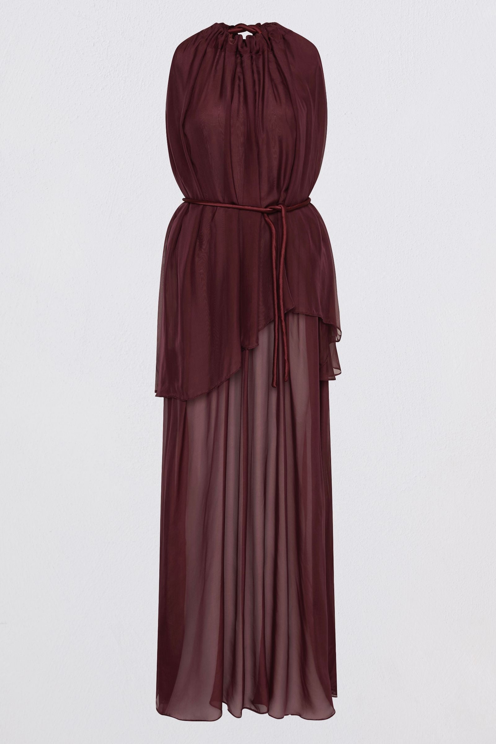 sleeveless, deep burgundy maxi dress with a tie-neck back detail, a defined waist, and a flowing layered skirt, set against a plain light gray studio background.