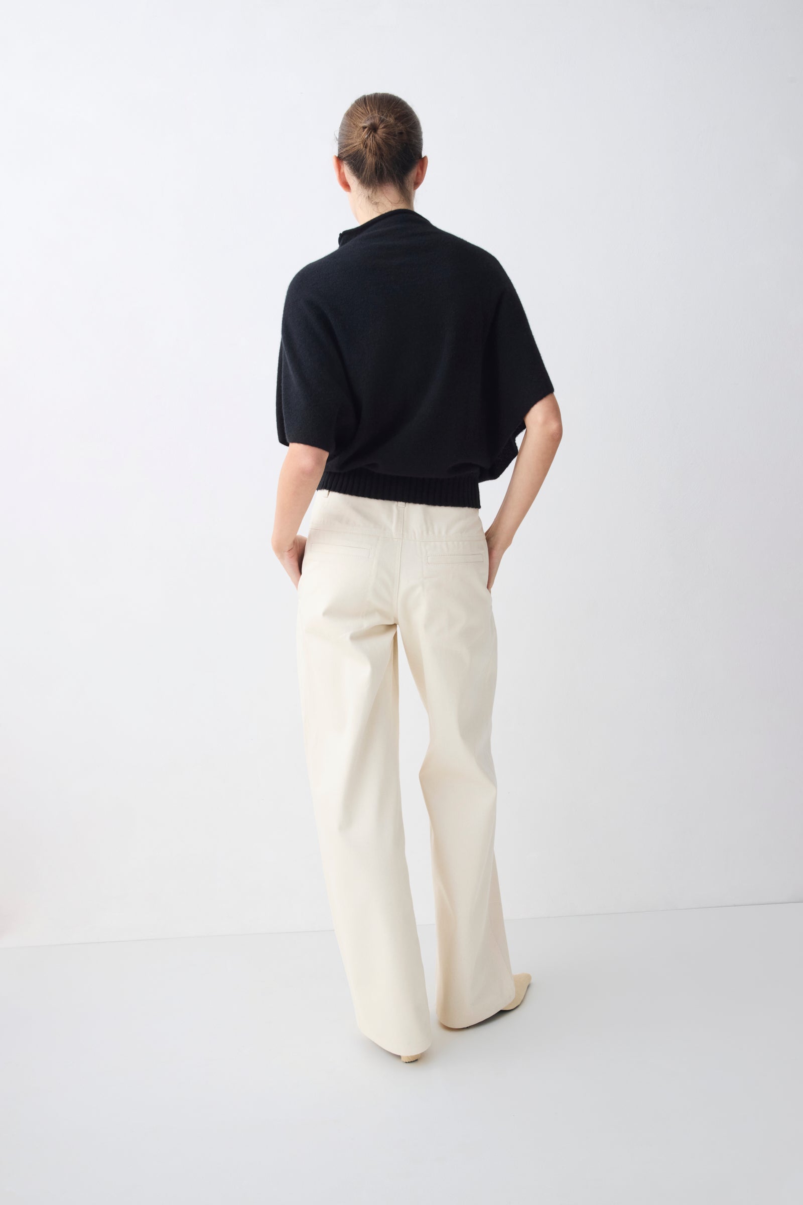 Person wearing a black shirt and white pants on a white background