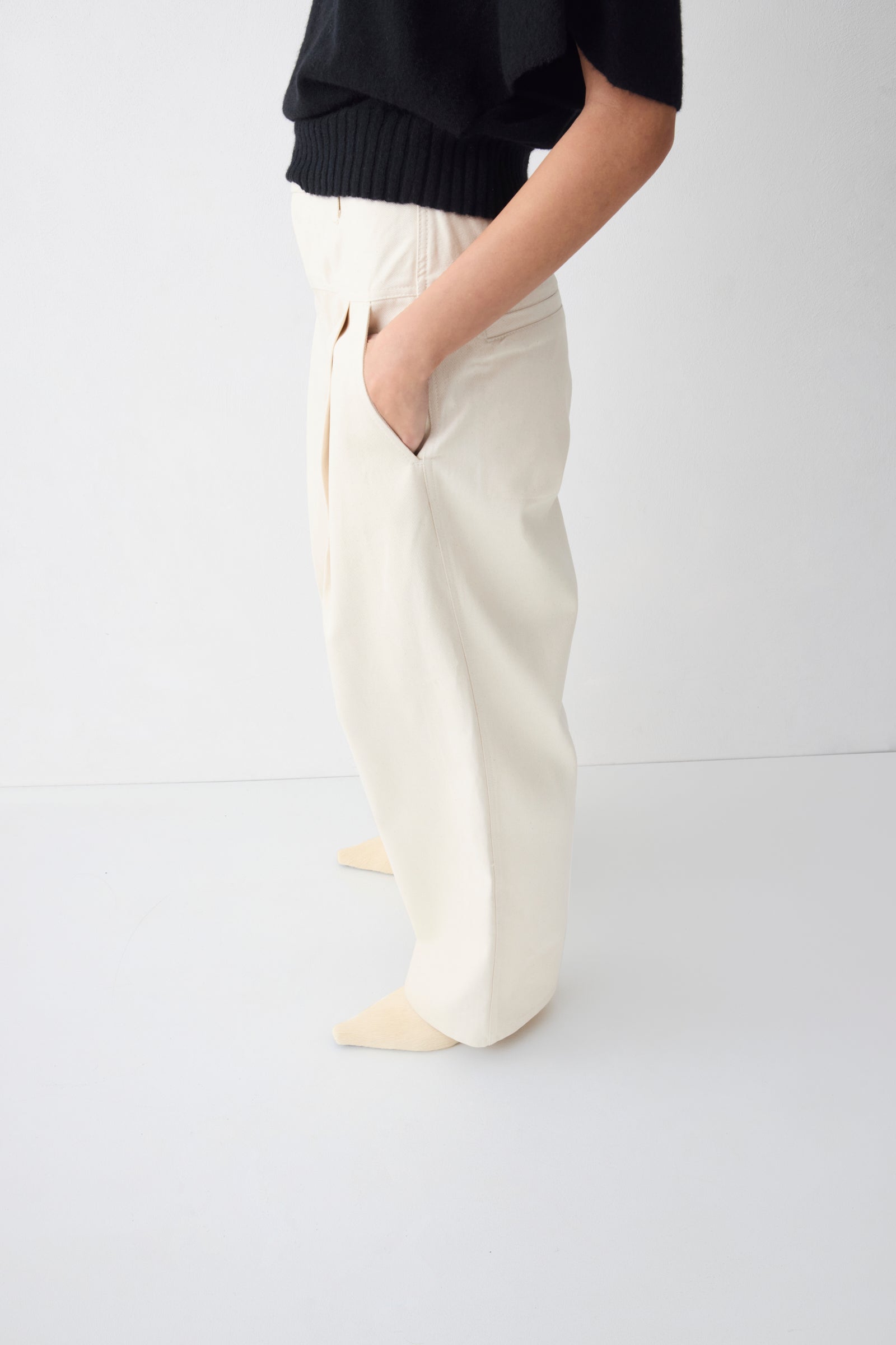 Person wearing white pants and a black top on a white background