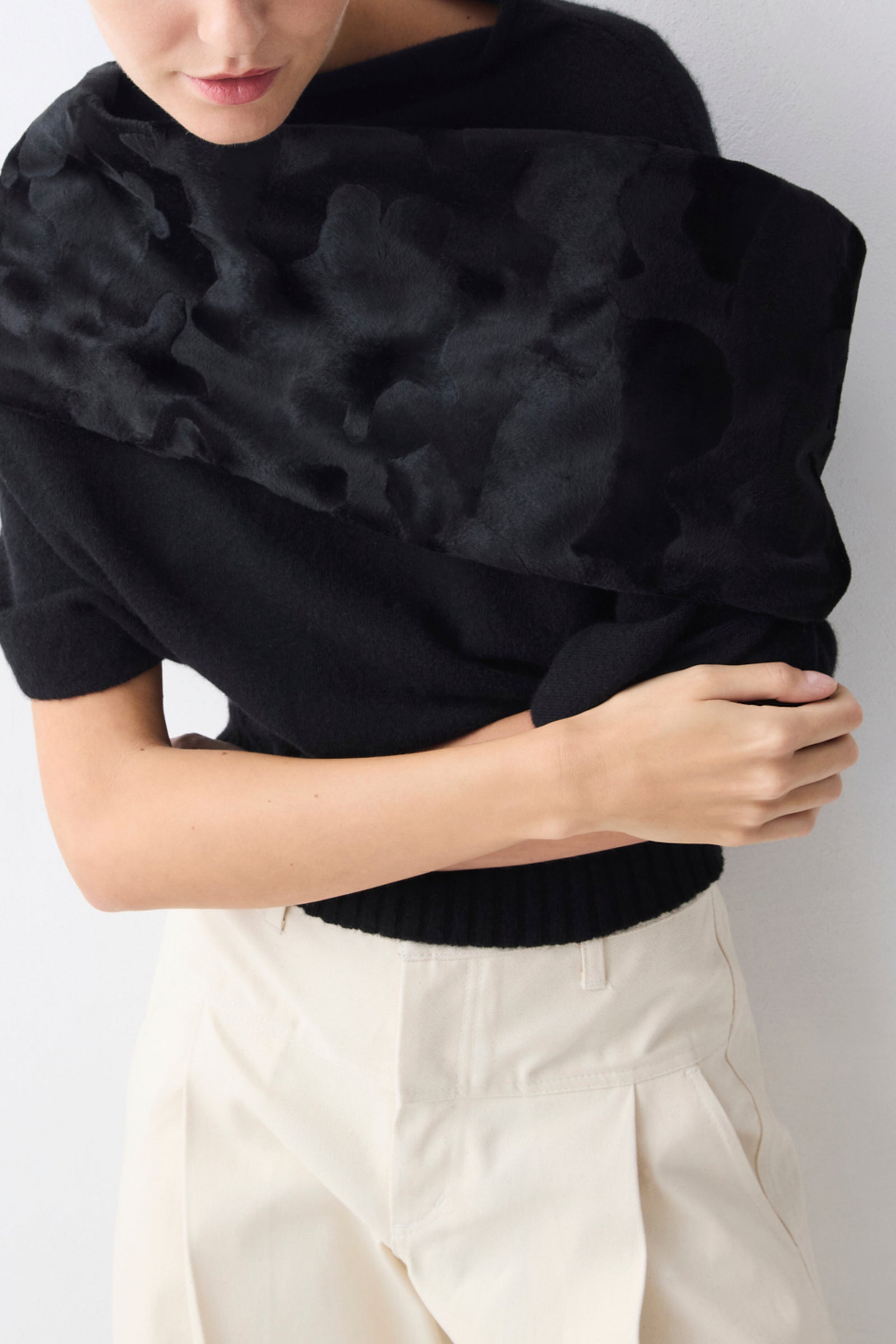 Person wearing a black sweater with textured fabric against a white background
