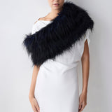 Woman wearing a navy fur shrug over a white dress against a plain background