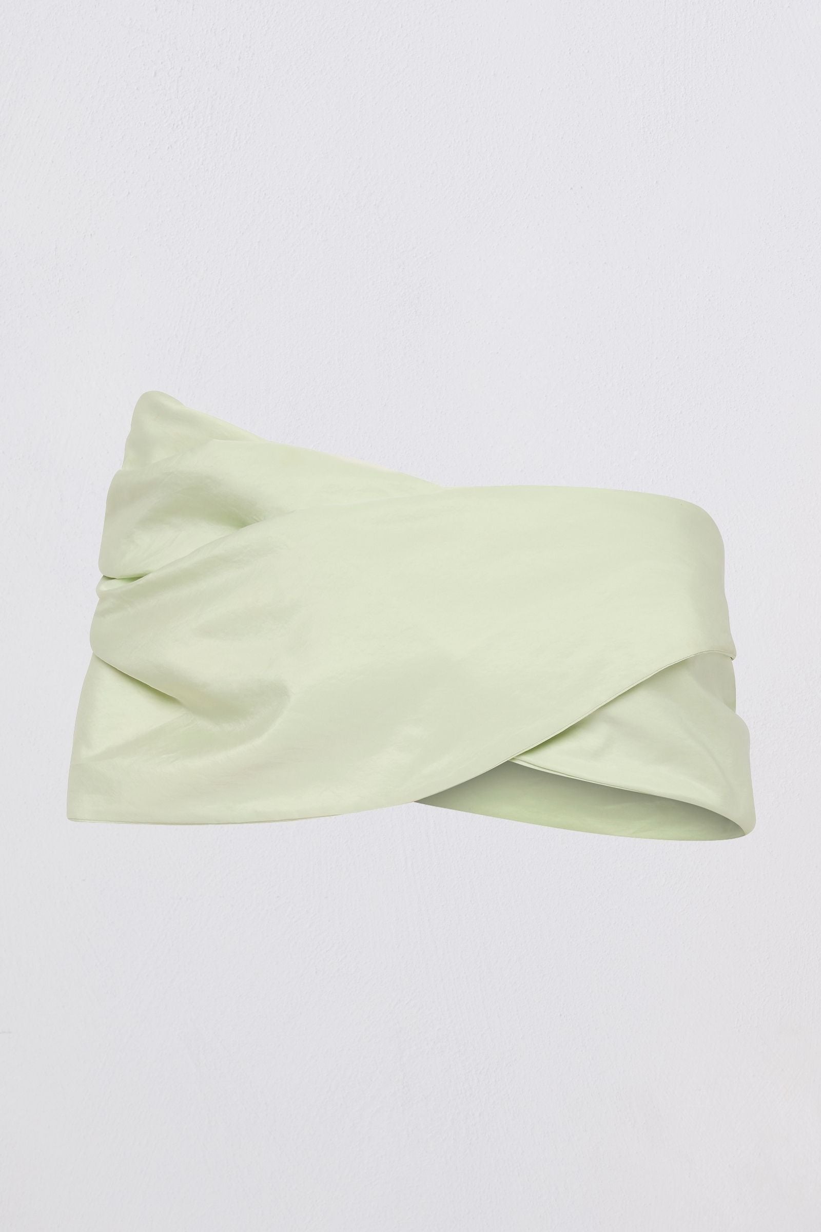 A pale mint green twisted headband made of smooth satin-like fabric, displayed against a clean white background.