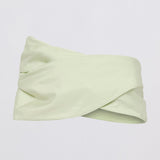 A pale mint green twisted headband made of smooth satin-like fabric, displayed against a clean white background.