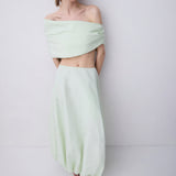 A model wearing a light mint green two-piece set consisting of an off-the-shoulder crop top and a matching high-waisted, voluminous maxi skirt, paired with black strappy sandals against a plain light gray studio background.