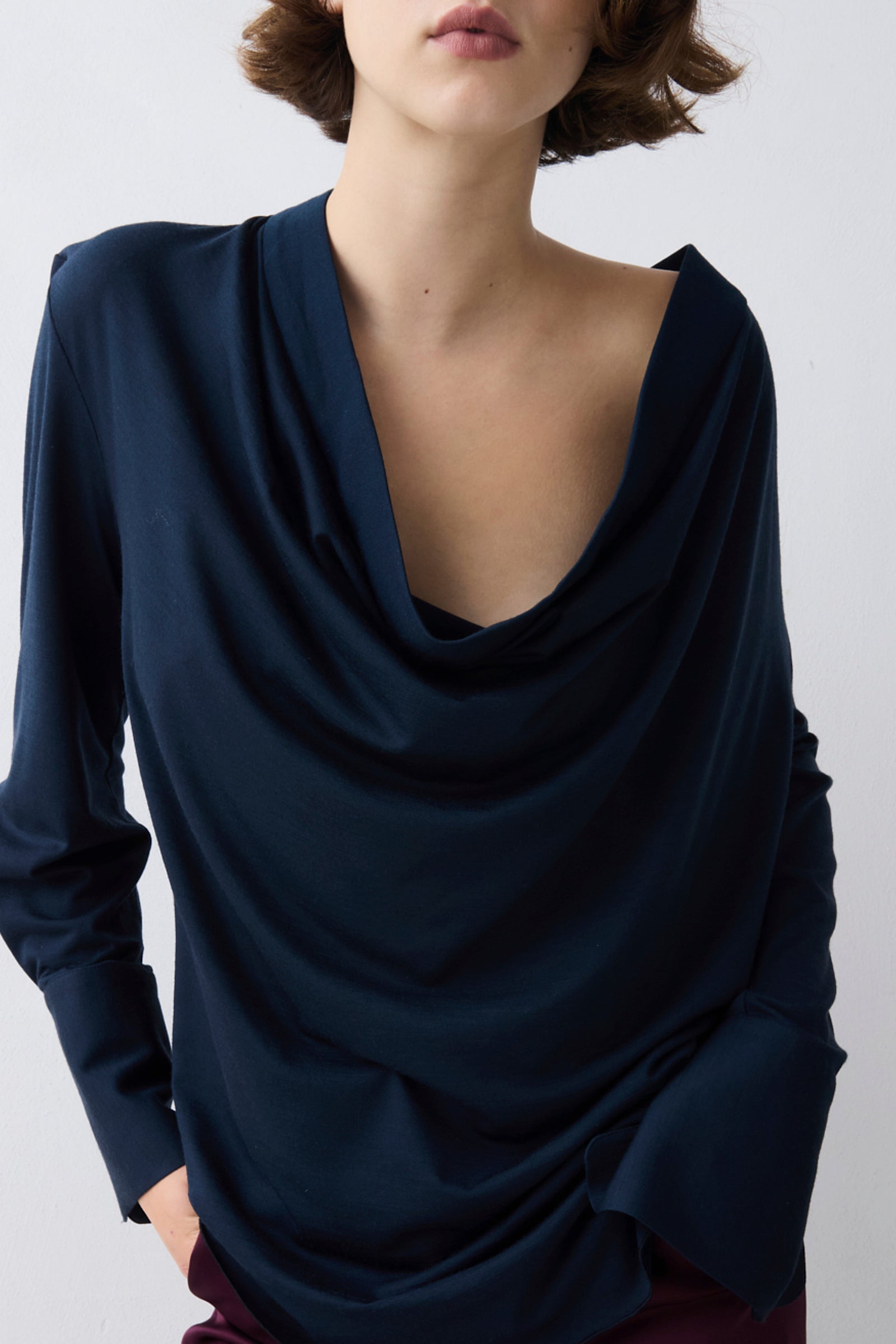 Navy blue draped top worn by a person on a white background