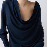 Navy blue draped top worn by a person on a white background