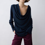 Woman wearing a navy blue top and purple pants against a white background
