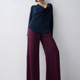 Woman wearing a navy top and maroon pants against a white background