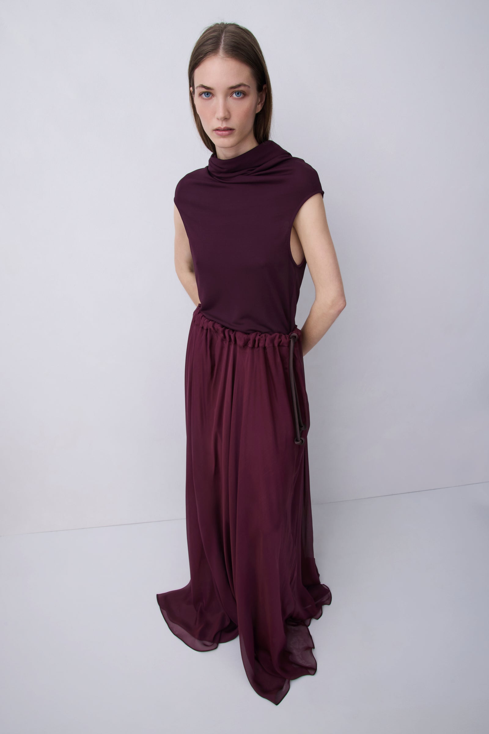 Plum jersey top with a relaxed fit, wide adjustable funnel neck and softly draped silhouette, photographed against a plain white studio background.