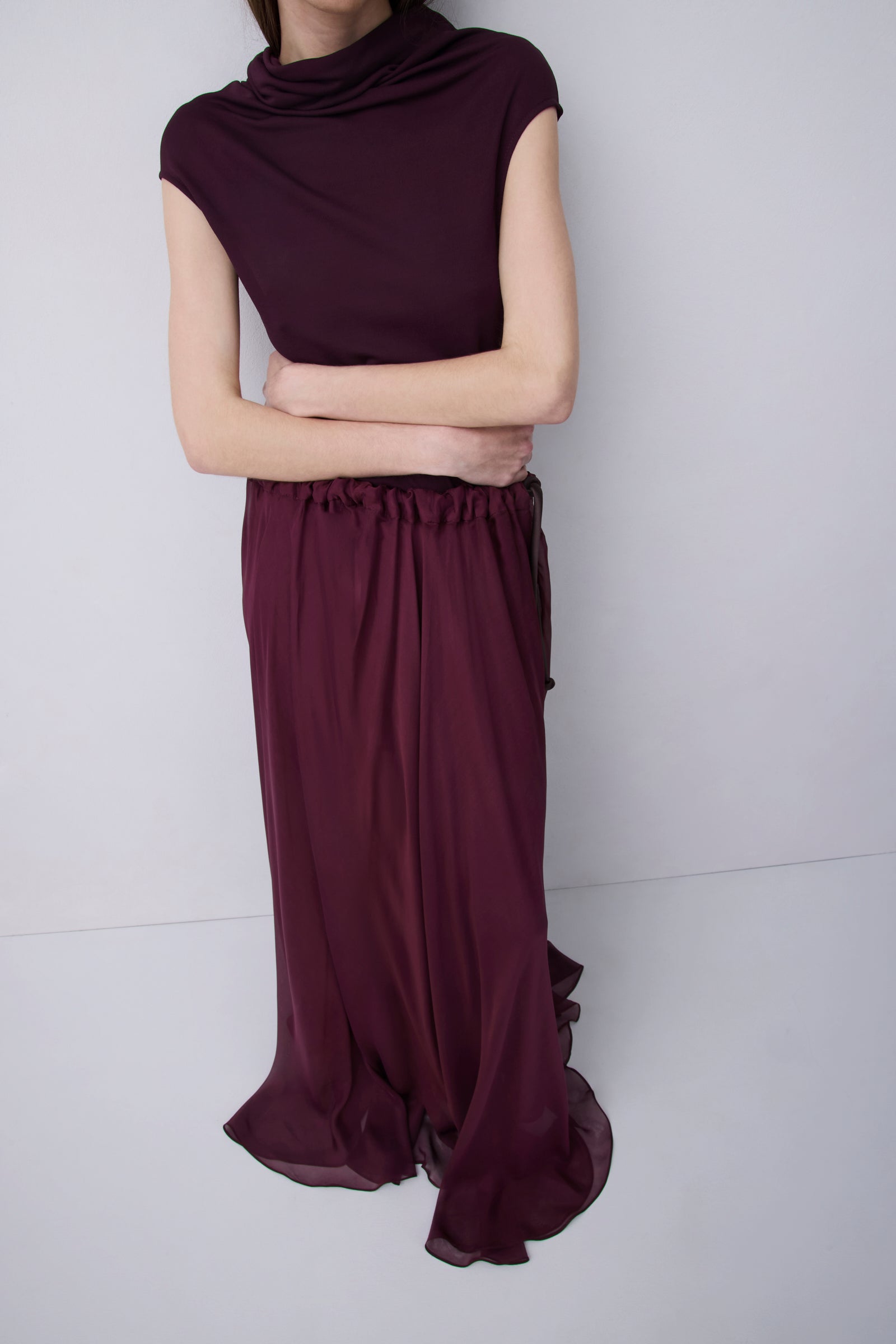 Plum jersey top with a relaxed fit, wide adjustable funnel neck and softly draped silhouette, photographed against a plain white studio background.