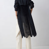 Person wearing a long black coat with a white background