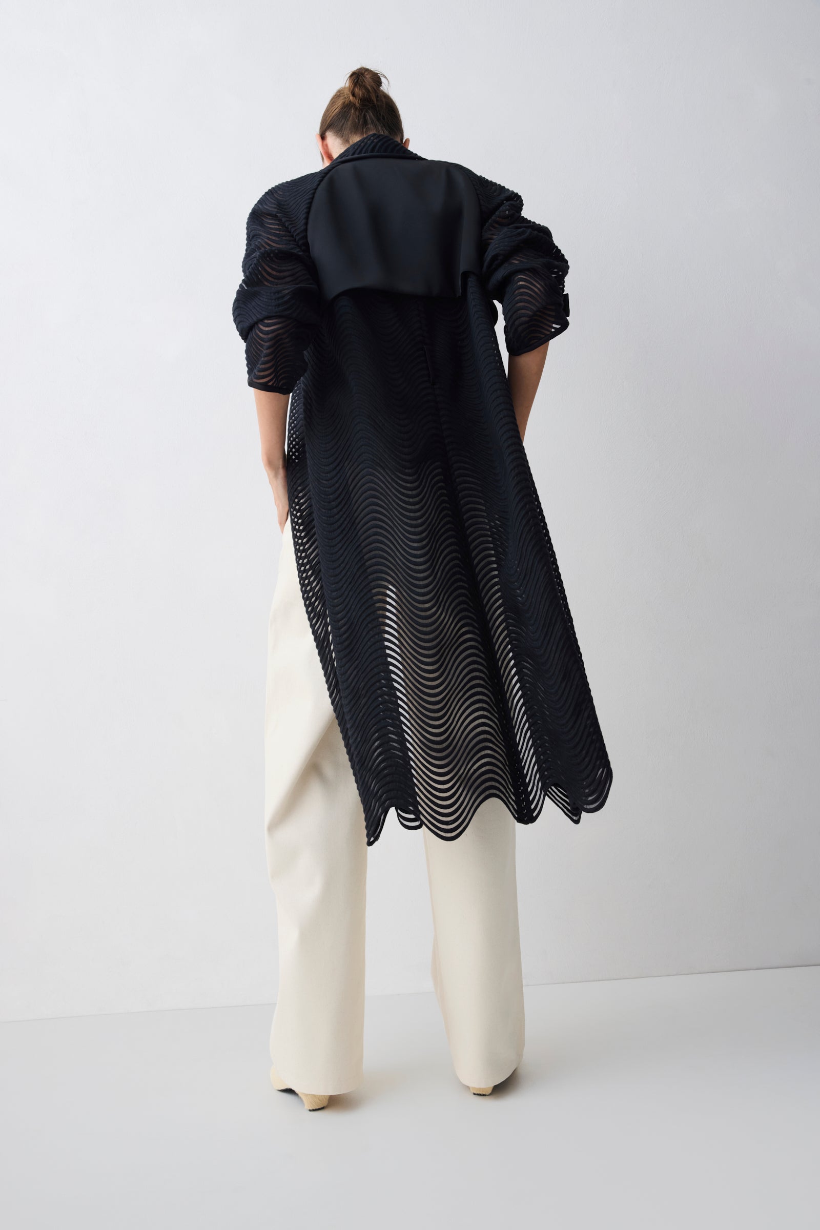 Person wearing a long black coat with a white background