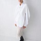 Person wearing a white shirt and black boots on a plain background