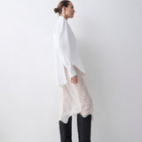 Person wearing a white long-sleeve top, patterned skirt, and black knee-high boots on a white background