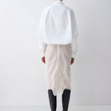 Person wearing a white shirt and patterned skirt with black boots on a white background
