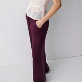 Person wearing a white patterned top and purple pants on a plain background